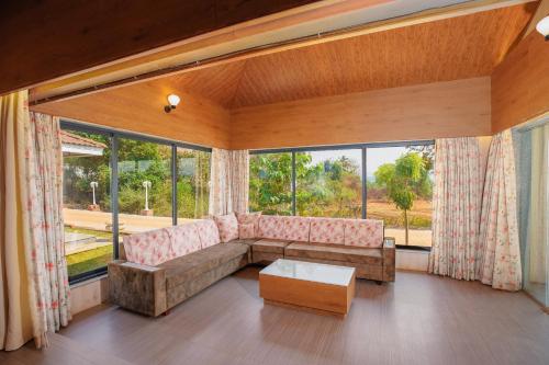 a living room with a couch and a large window at Urmilaa Green County Resort 35 KM From Kolhapur in Kolhapur