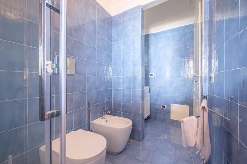 Un baño con azulejos azules, inodoro y lavabo. en Villa Chiara, en Lipari