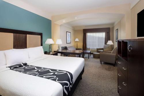 a hotel room with a bed and a living room at La Quinta by Wyndham Savannah Airport - Pooler in Savannah