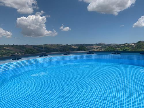 una piscina con cielo azul y nubes en Gastronomic B&B CarloCarla, en Monte San Pietrangeli
