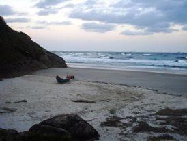 a person sitting on a beach near the ocean at Pousada Margareth in Ilha do Mel