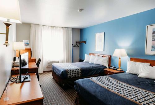 a hotel room with two beds and a desk at Travelodge by Wyndham Worland in Worland