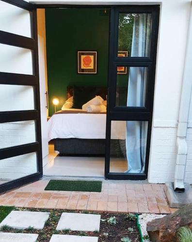 Una puerta que conduce a un dormitorio con cama en Modern studio with private garden, self check-in, en Johannesburgo
