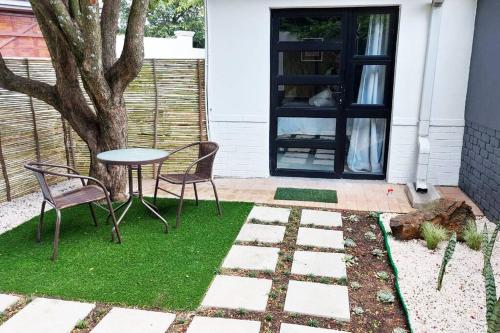 un patio con mesa, sillas y un árbol en Modern studio with private garden, self check-in, en Johannesburgo