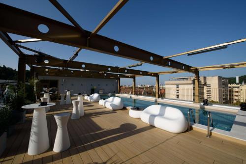a rooftop patio with white chairs and tables on a roof at Radisson Blu Aurum Hotel, Brasov in Braşov