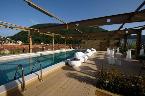 - une piscine avec des chaises blanches sur une terrasse en bois dans l'établissement Radisson Blu Aurum Hotel, Brasov, à Braşov