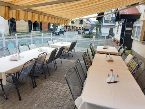 - une rangée de tables et de chaises sur la terrasse dans l'établissement Landhotel Westerwaldgrill, à Höhn