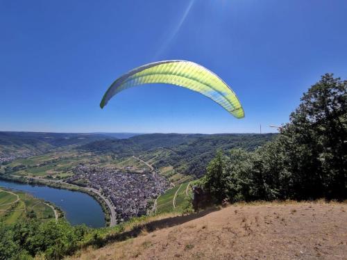 a person flying a parachute on top of a hill at Ritterstube - Eifelstuben mit Charme, Nähe See und Burg, außergewöhnlich, Vulkaneifel in Ulmen