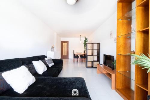 sala de estar con sofá negro y TV en Mediterranean Way - La Placeta en Cambrils