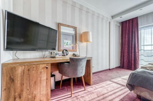 una camera d'albergo con scrivania e grande TV di Hotel Swing a Cracovia