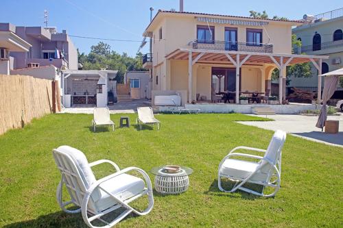 a group of chairs sitting in the yard of a house at Pilot's Cottage Villa With Sea View in Tavronitis