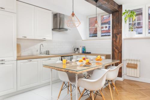 a kitchen with white cabinets and a table with chairs at ECRU Warsaw Apartment near Vistula River WWA1 in Warsaw