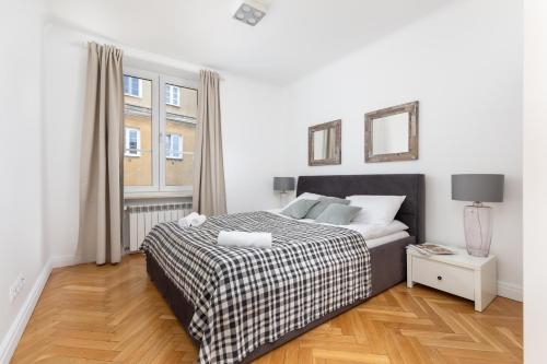 a white bedroom with a bed and a window at ECRU Warsaw Apartment near Vistula River WWA1 in Warsaw