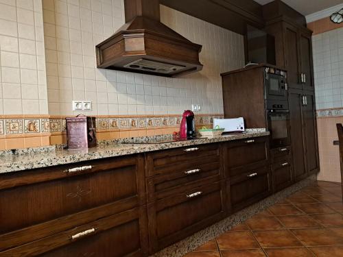 a kitchen with wooden cabinets and a stove at Casa El Albero (Torcal-Caminito del Rey) in La Joya