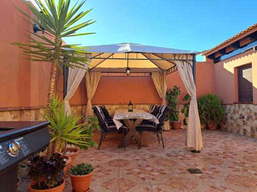 a patio with a table and chairs under an umbrella at Casa El Albero (Torcal-Caminito del Rey) in La Joya