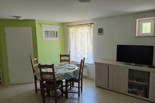 ein Wohnzimmer mit einem Tisch, Stühlen und einem TV in der Unterkunft Quiet cocoon near the city centre in Gérardmer