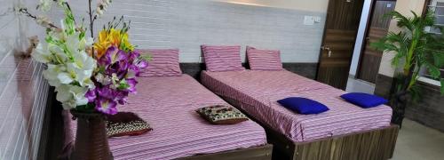 two beds with purple sheets and a vase with flowers at N S CHITHRA MAHAL in Tiruvannāmalai