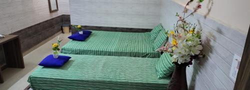 two green beds with blue pillows in a room at N S CHITHRA MAHAL in Tiruvannāmalai