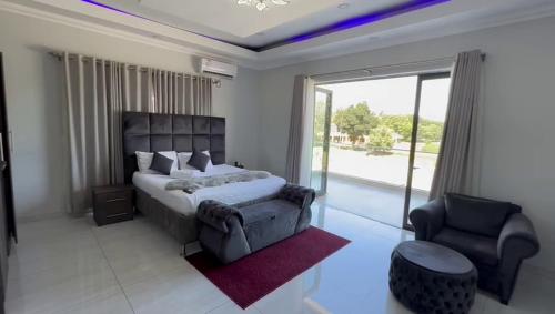 ein Schlafzimmer mit einem Bett, einem Stuhl und einem Fenster in der Unterkunft Lifestyle Lodge Hotel in Vereeniging