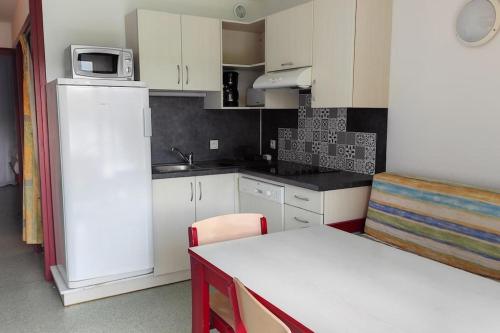 Elle comprend une petite cuisine équipée d'un réfrigérateur blanc et d'une table. dans l'établissement Cambo les Bains Piscine Vue Montagnes, à Souraïde