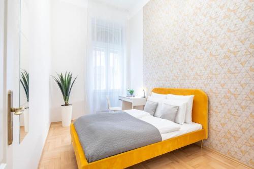 a bedroom with a bed with a yellow headboard at Cityscape Apartments Theresa in Budapest