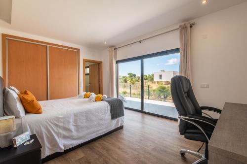 a bedroom with a bed and a chair and a large window at Casa do Pomar, Piscina Privada, Prainha Alvor! in Alvor