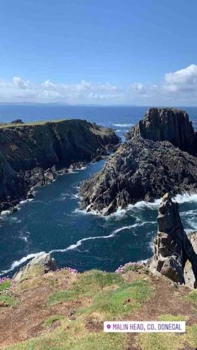 a view of the ocean with rocks in the water at Cosy Portmor Log Cabin- Sea views, Deck & Relaxation in Malin Head