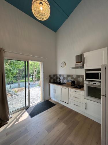 une cuisine avec des placards blancs et une grande fenêtre dans l'établissement Au domaine des sources, à Grosbreuil