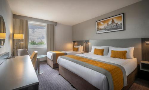 a hotel room with two beds and a window at Maldron Hotel Belfast International Airport in Aldergrove