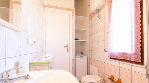 a bathroom with a sink and a toilet and a window at Sardinianworld - La Finestra Sul Mare in Torre Grande