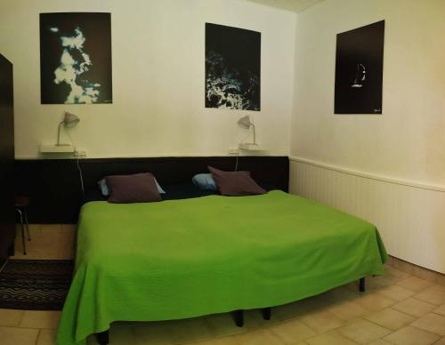 Cama verde en habitación con 2 lámparas en Au bord de la Sioule, en Menat