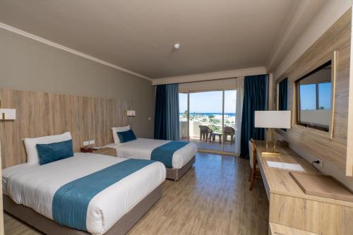 a hotel room with two beds and a flat screen tv at Seven Seas Jolie Bay - Ultra All Inclusive in Hurghada