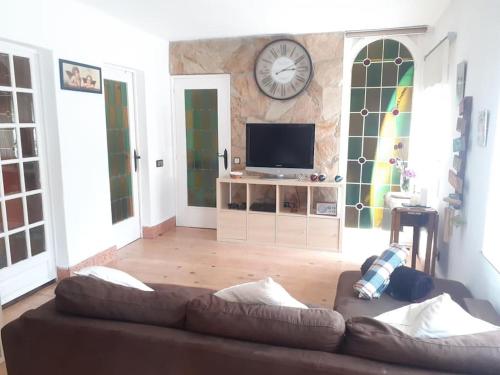 ein Wohnzimmer mit einem Sofa und einer Uhr an der Wand in der Unterkunft Maresme´s corner in Sant Andreu de Llavaneres