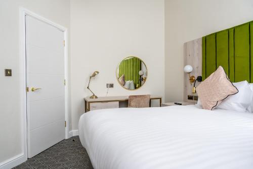 a bedroom with a white bed and a green headboard at Trafford Hall Hotel Manchester, Trademark Collection by Wyndham in Manchester
