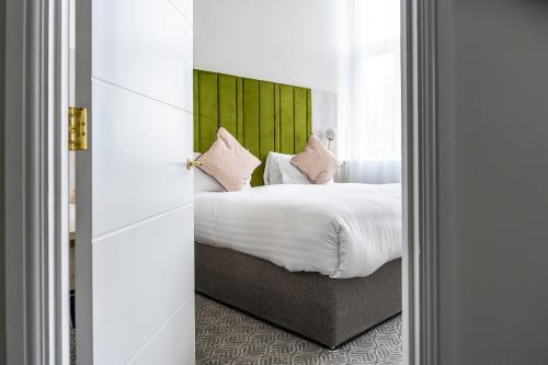 a bedroom with a bed with white sheets and pink pillows at Trafford Hall Hotel Manchester, Trademark Collection by Wyndham in Manchester