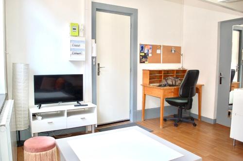 - un salon avec un bureau, une télévision et une chaise dans l'établissement Cocon avec cour citadelle Vauban, à Lille