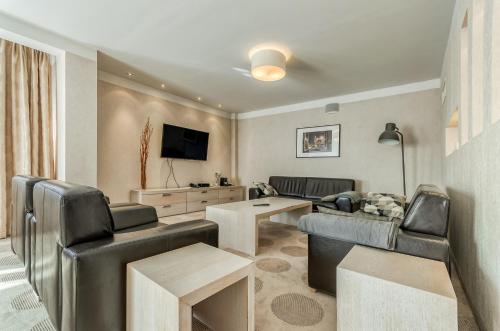 a living room with leather furniture and a flat screen tv at Hotel Swing in Kraków
