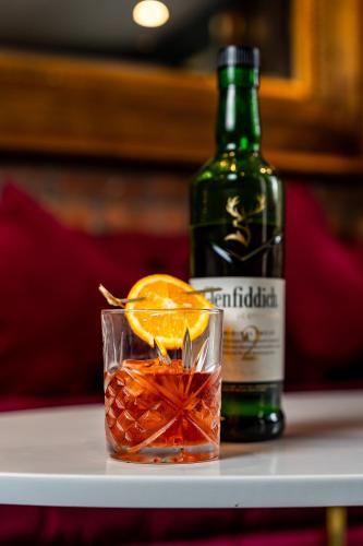 a bottle of alcohol and a glass with an orange slice at Trafford Hall Hotel Manchester, Trademark Collection by Wyndham in Manchester