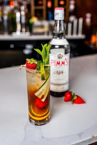 a drink with strawberries and a bottle of gin at Trafford Hall Hotel Manchester, Trademark Collection by Wyndham in Manchester
