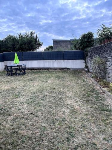 - une table de pique-nique avec un parasol vert dans la cour dans l'établissement Downtown cozy cottage - 4 pl -, à Château-Gontier