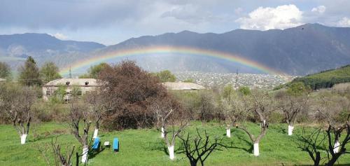 a rainbow over a field with trees and houses at Odzun Hotel in Alaverdi