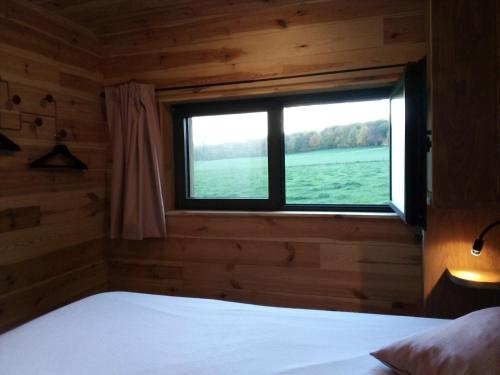 1 dormitorio con ventana en una cabaña de madera en La Bucolique de Tahier en Ohey
