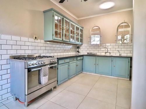 cocina con armarios azules y fogones en Featherwood Farm & Nyala Lodge, en Rayton