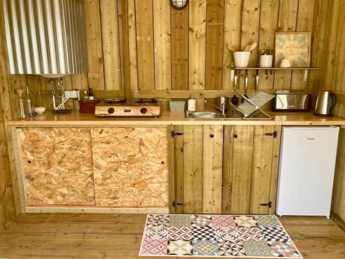 a kitchen with wooden walls and a counter with a sink at Tente Glamping nature et océan, Rogil in Rogil