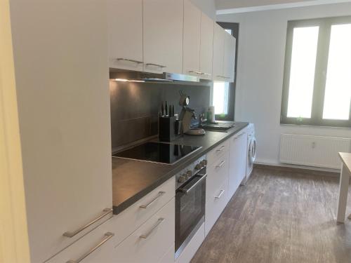 a kitchen with white cabinets and a stove top oven at Art-Appartement in Bielefeld