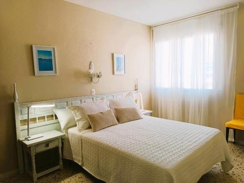 a bedroom with a white bed and a window at Villa Service - Torre Barot 5º in Calafell