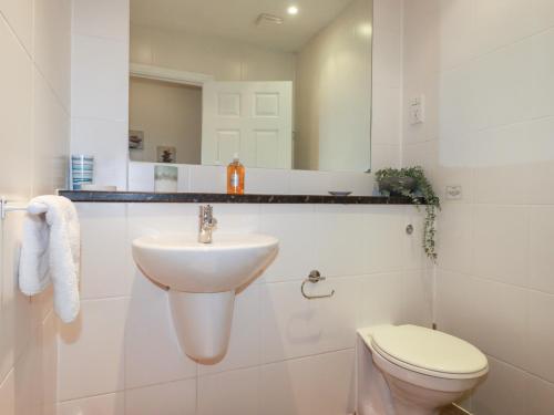 a white bathroom with a sink and a toilet at Far Horizons in Newquay