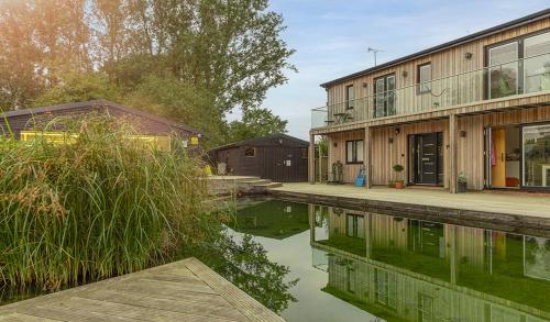 a house next to a body of water at Piglets Boutique Country Stay - winner Best B&B and Guest House of the Year - VisitEngland 2023 in Saffron Walden