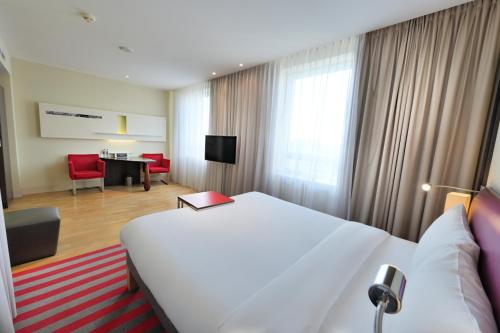 a hotel room with a large white bed and a desk at Mercure Warszawa Grand in Warsaw