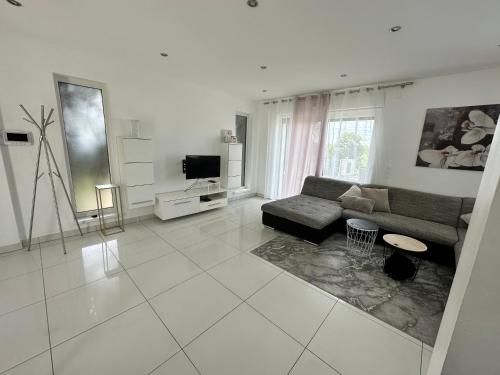 a white living room with a couch and a tv at Résidence Foch in Lingolsheim
